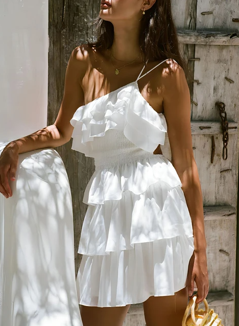 Model mengenakan dress flowy dengan potongan asimetris dan aksesori topi lebar, sesuai tren fashion 2024